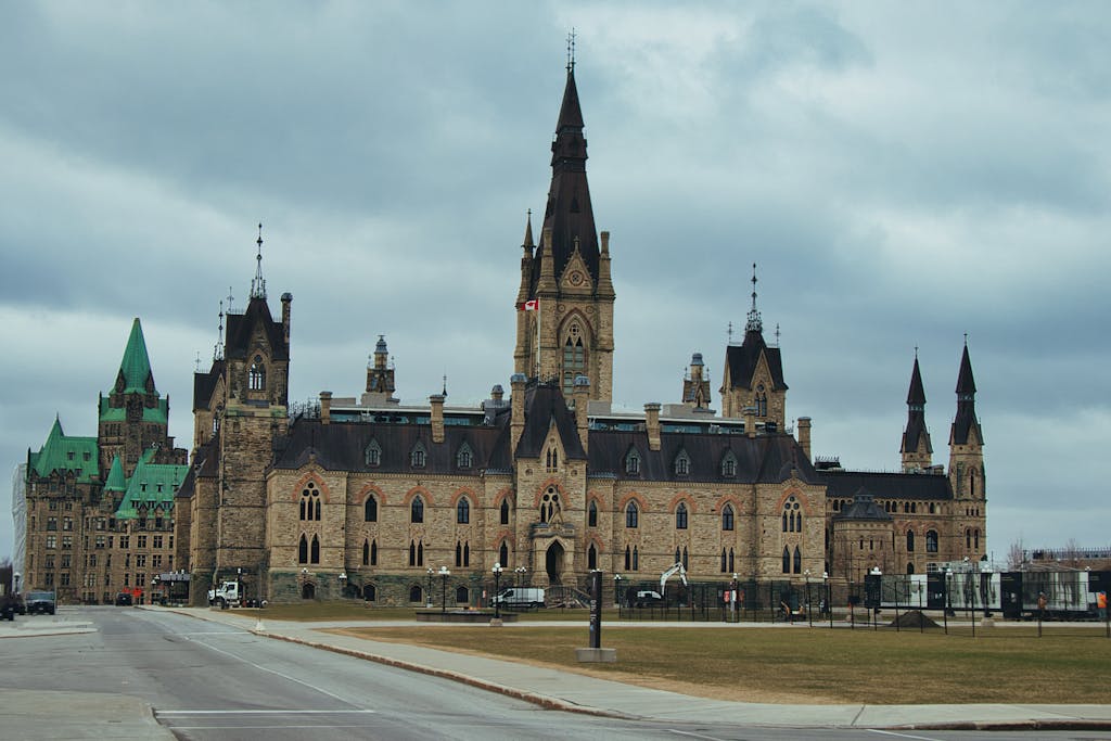 Majestic view of Canada's Parliament Buildings in Ottawa under a cloudy sky, showcasing Gothic Revival architecture.
